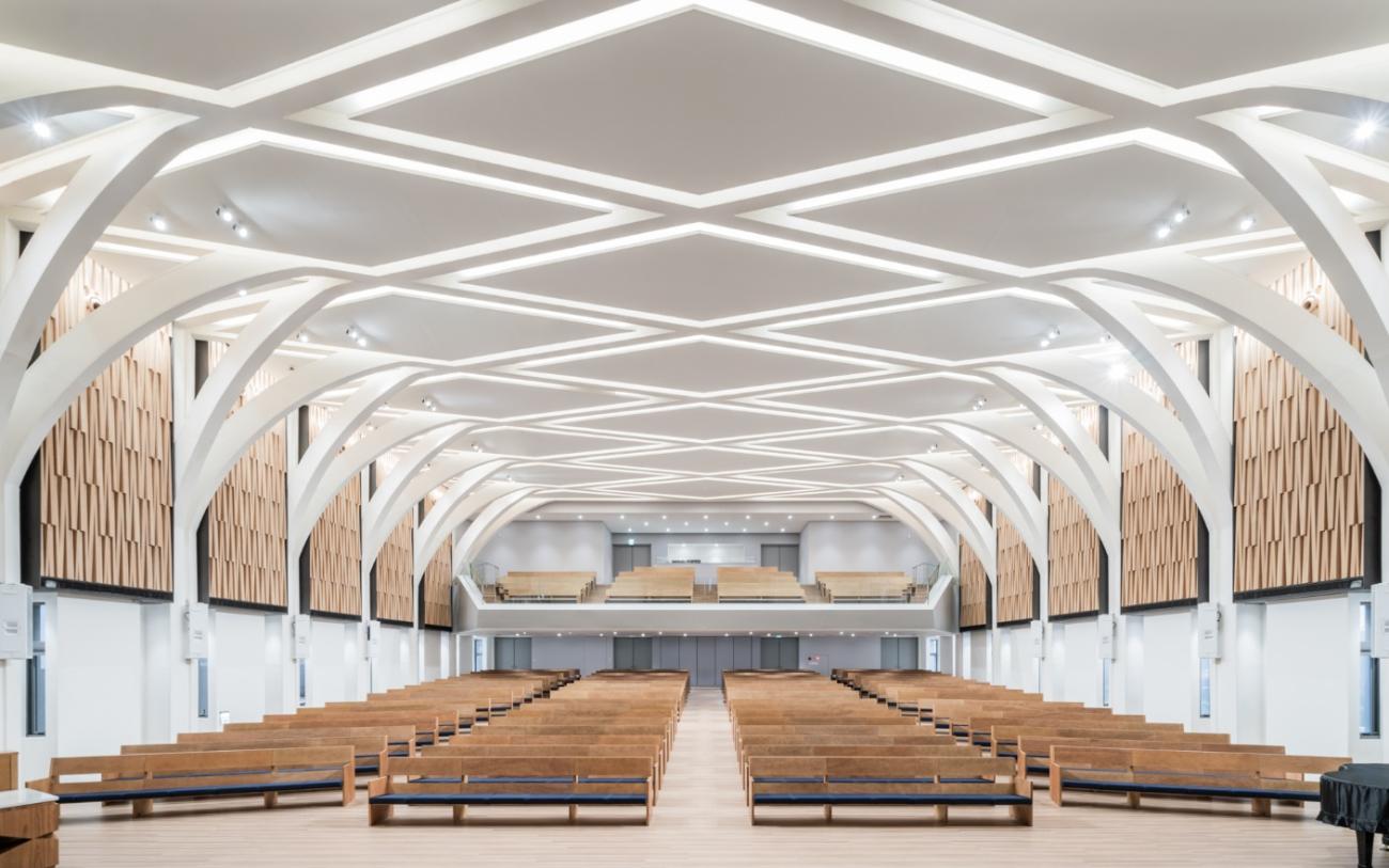 Cavernous room with geometric ceiling and rows of wooden pews