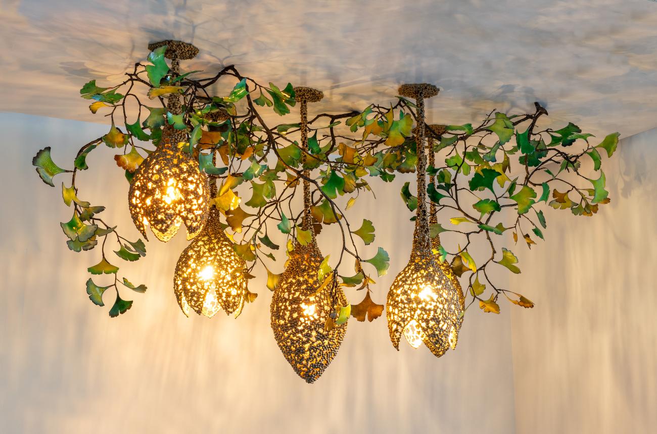 Four gold objects hang from the ceiling surrounded in greenery