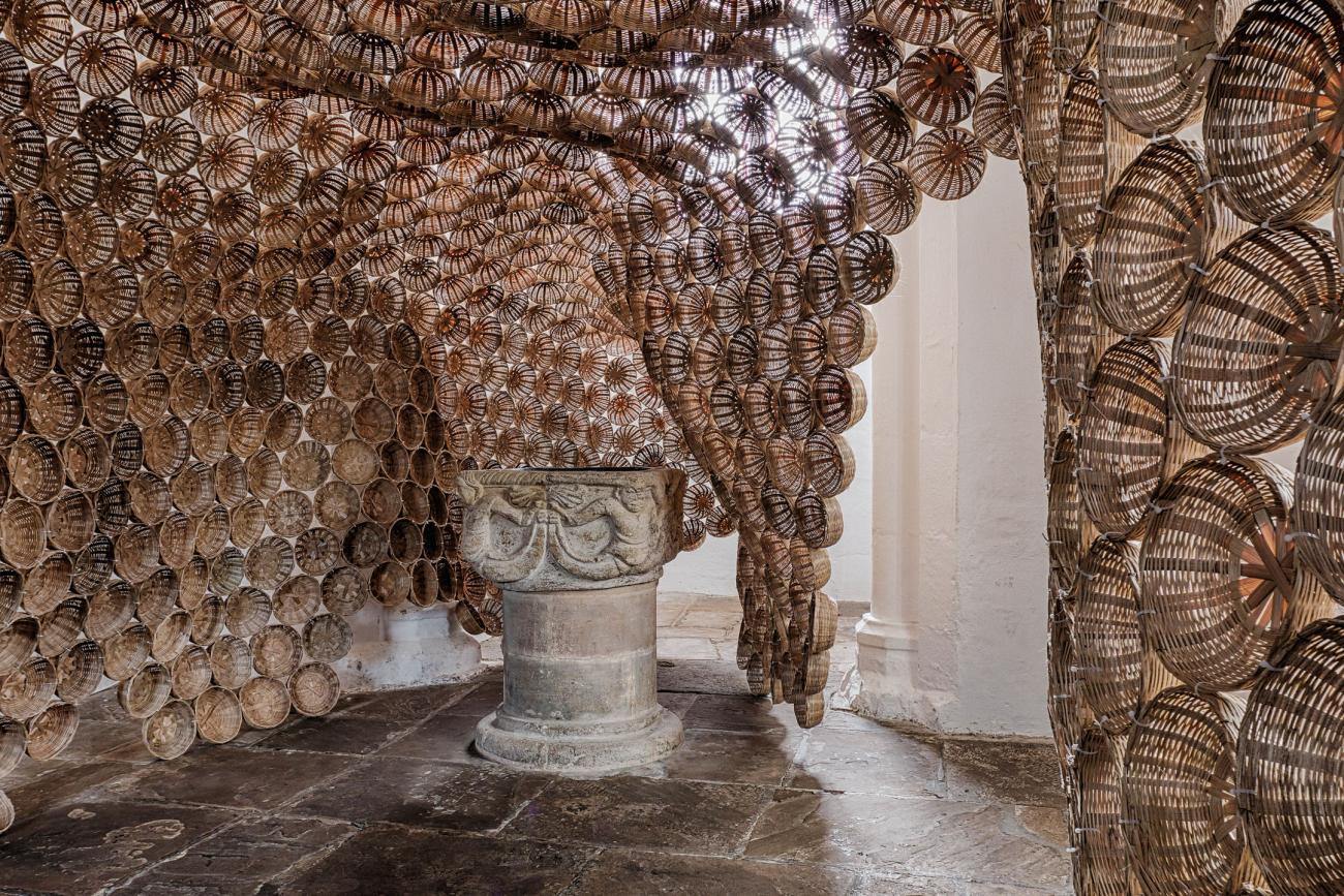 Art sculpture composed on baskets lined against the walls of an exhibition room